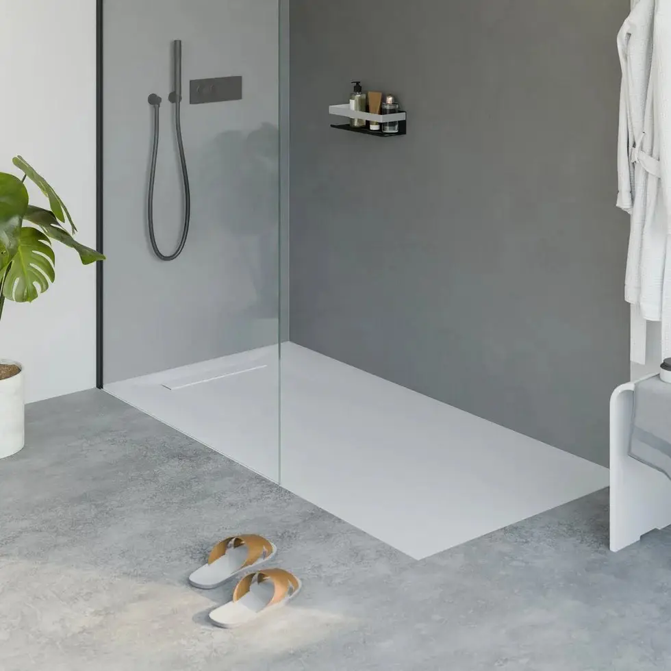 Bodengleiche Dusche mit flacher Duschfläche und Glaswand in einem modernen grauen Bad, davor Badeschuhe auf dem Boden