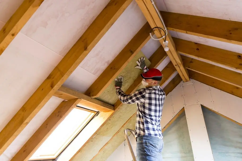 Handwerker dämmt die Dachschräge zwischen den Sparren