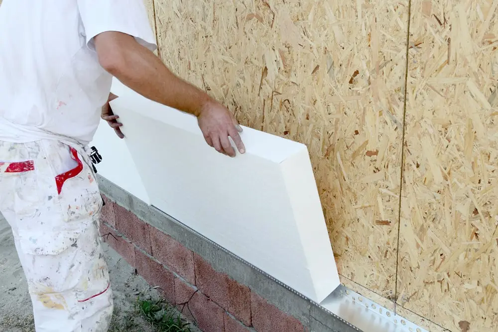 Handwerker setzt eine Dämmplatte an die Außenwand