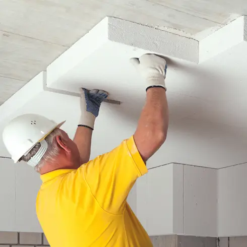 Handwerker montiert Dämmplatten an der Kellerdecke
